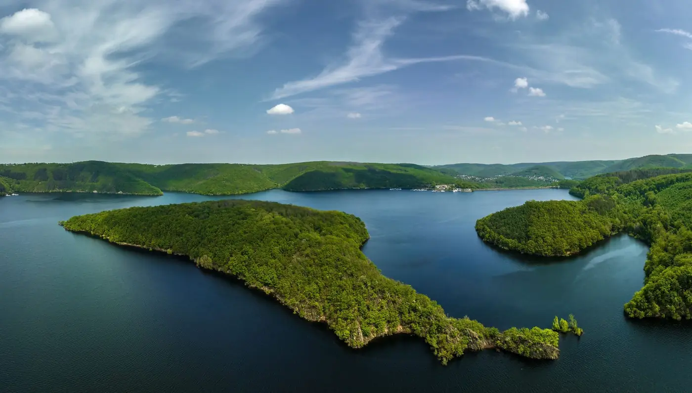 Luchtfoto van de Rursee met beboste schiereilanden en heuvels onder een blauwe hemel