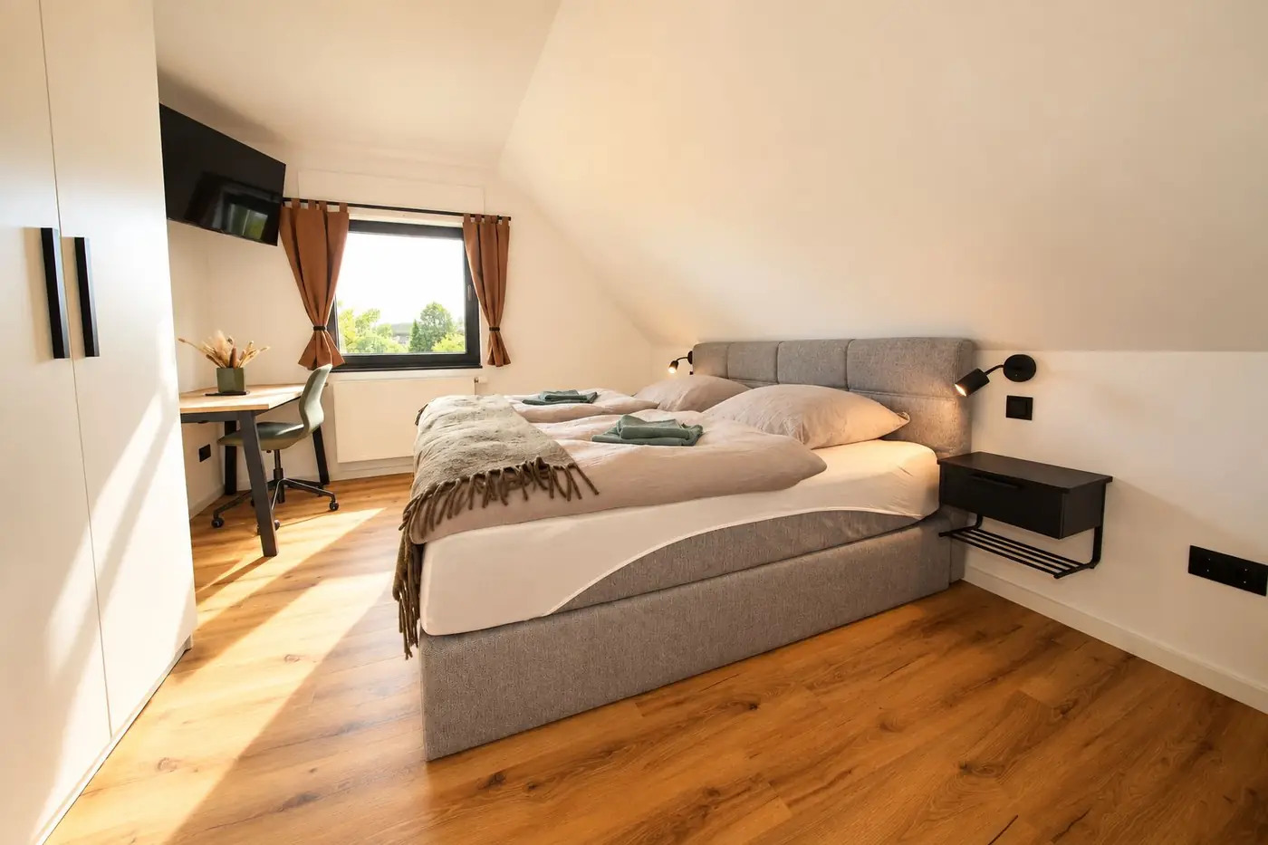 Slaapkamer met boxspring, kledingkast en raam in het schuine dak