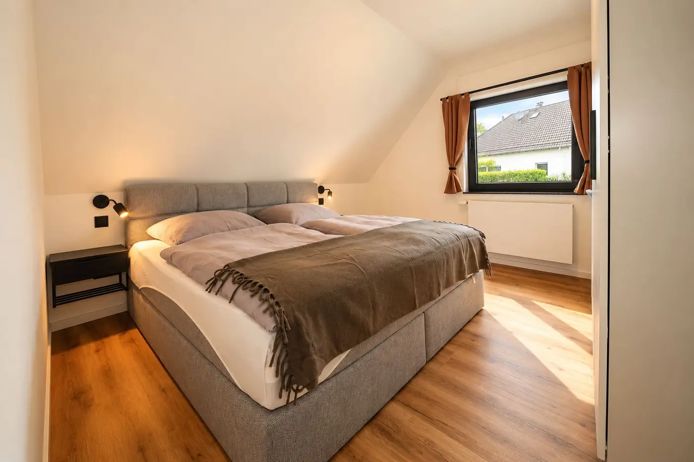 Slaapkamer met grijze boxspring en nachtkastje